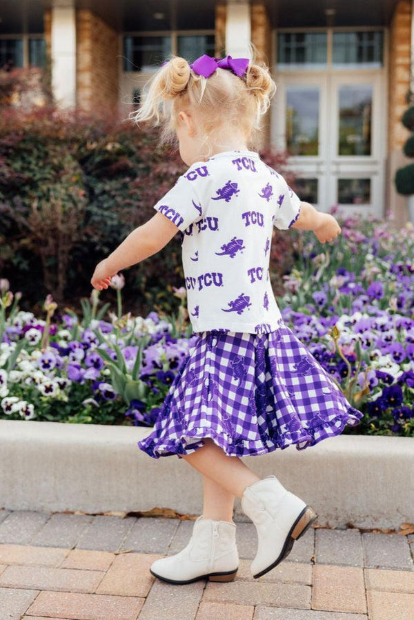 Toddler girl wearing TCU girl ruffle skort in purple gingham with matching TCU shirt and white boots
