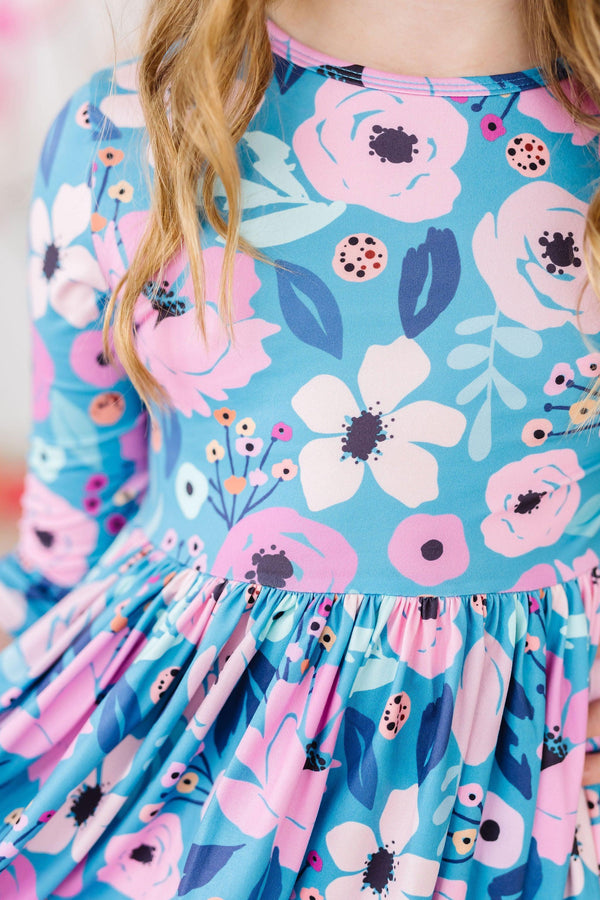 Girl wearing teal floral twirl dress for girls with 3/4 sleeves and pink blue flower pattern