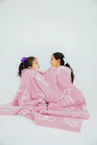 Girls pink throw blanket with white bow patterns wrapped around two kids cozy and soft