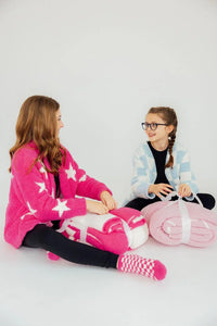 Two girls sitting with pink and pastel blue cozy throw blankets from Mila & Rose, soft and warm for kids
