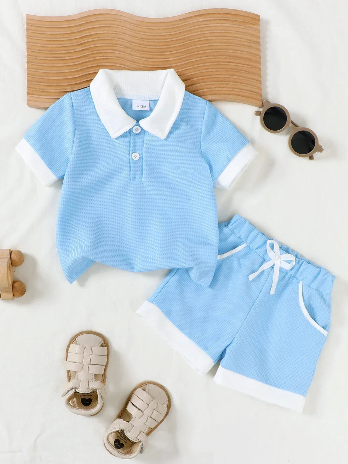 light blue toddler knit shorts set with white collar and trim laid flat with tan headband and beige sandals