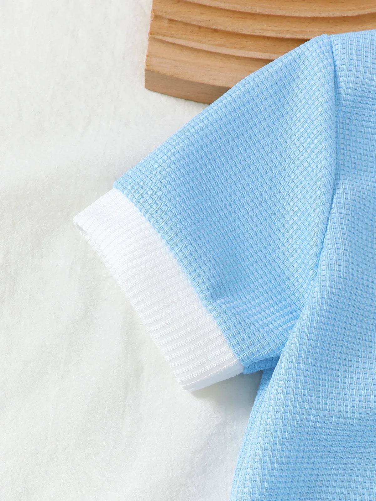 Close-up of a baby blue toddler knit shorts set sleeve with white cuff detail for toddlers