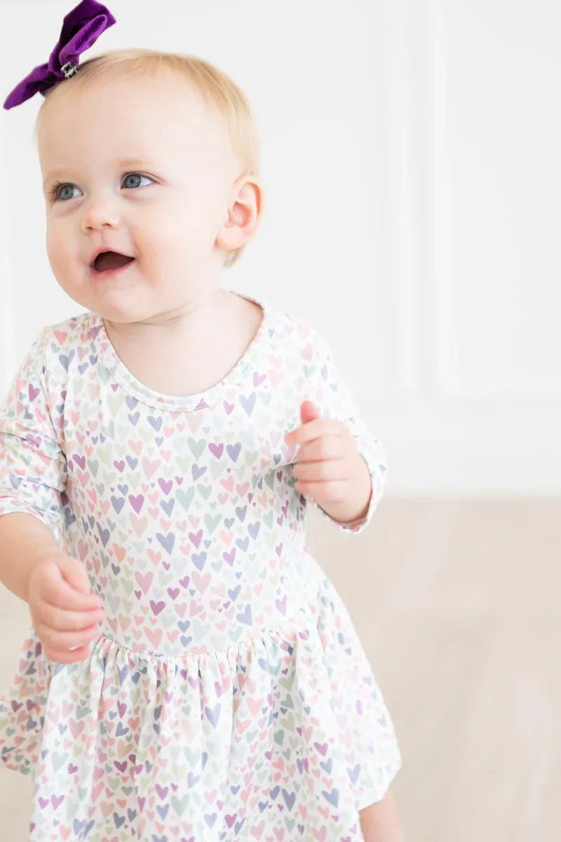 Toddler girl wearing Mila & Rose toddler twirl dress with 3/4 sleeves and pastel heart print