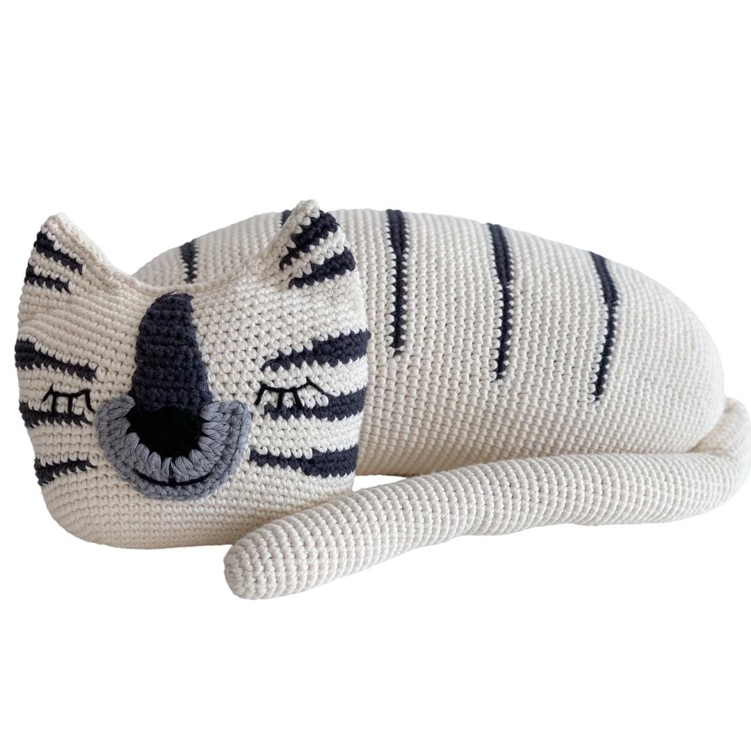 White crochet tiger with dark stripes resting on its side. Organic cotton stuffed animal toy perfect for reading time or as a child's gift.