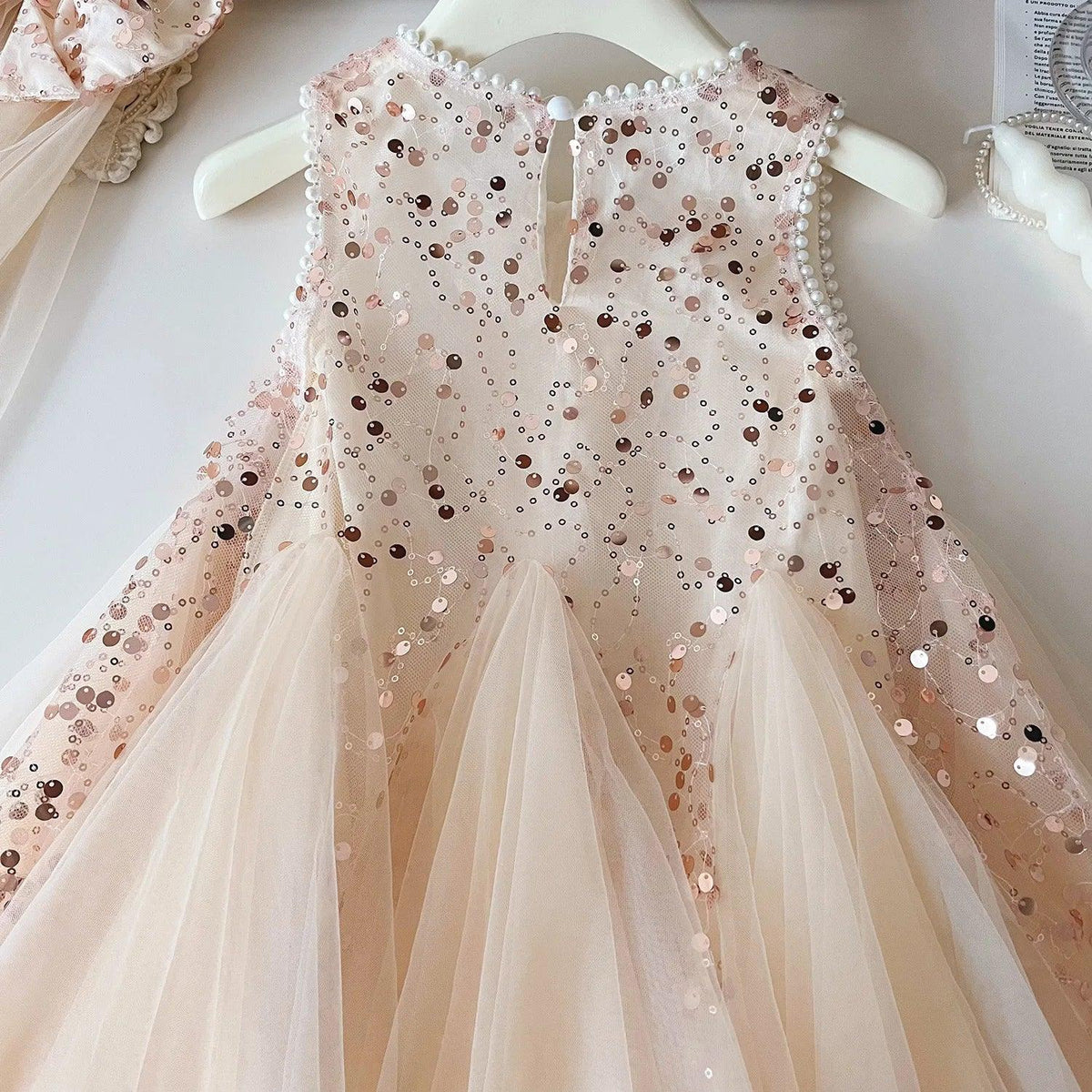Pink tulle party dress for girls with sequins and sleeveless design hanging on white hanger
