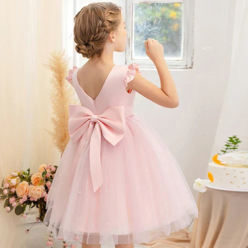 girls light pink tulle party dress with large bow back and ruffle cap sleeves for toddlers