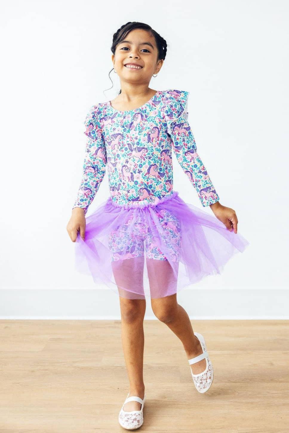 young girl wearing lavender tutu shorts for girls twirling with a floral long sleeve top