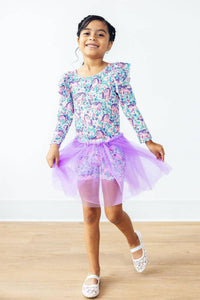 young girl wearing lavender tutu shorts for girls twirling with a floral long sleeve top