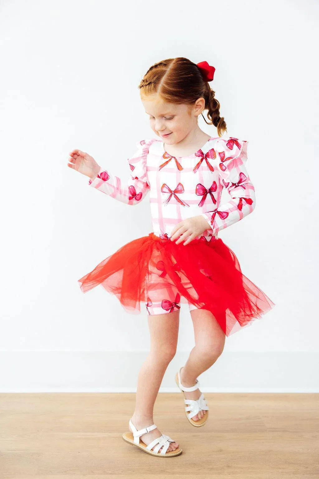 Toddler girl wearing red tutu shorts for girls with attached tulle skirt and white sandals