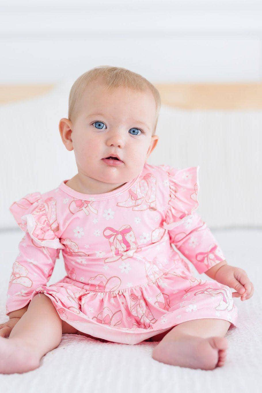 baby girl wearing pink 3/4 flutter twirl bodysuit sitting on white surface