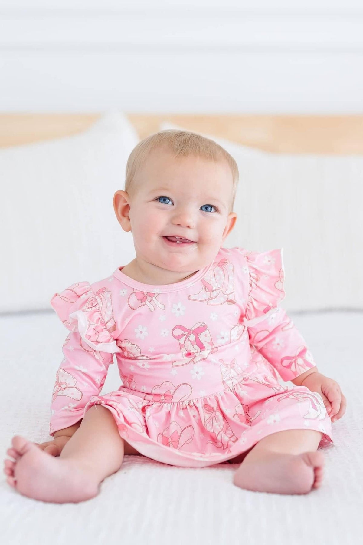 baby girl wearing pink twirl bodysuit with 3/4 flutter sleeves sitting and smiling