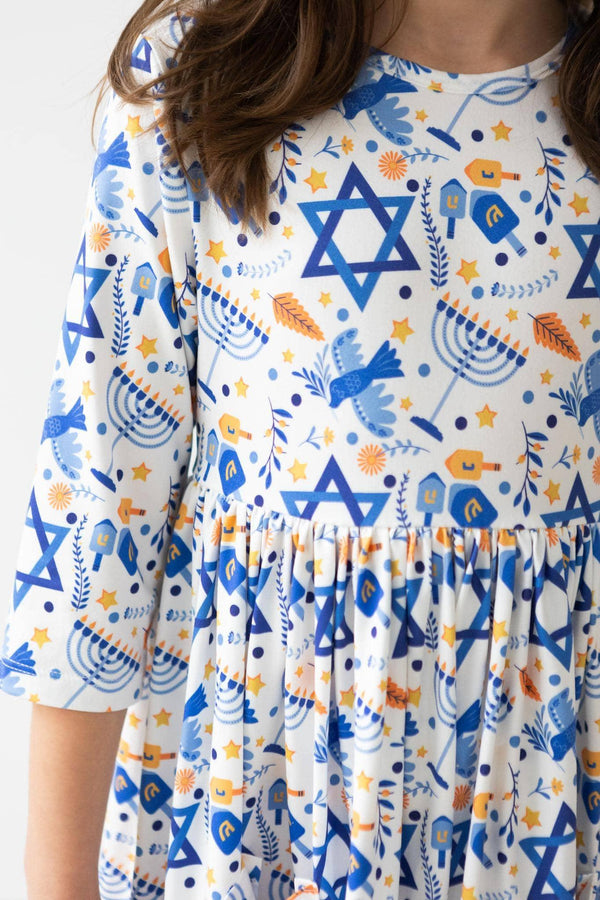 Girls white twirl dress with sleeves featuring blue menorahs and Star of David pattern