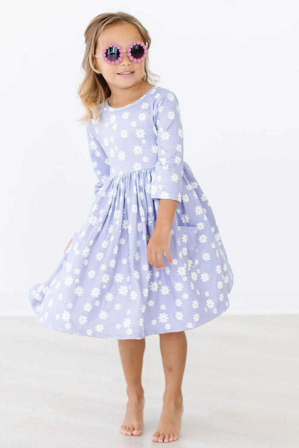 Young girl wearing lavender twirl dress for girls with white floral print posing barefoot indoors