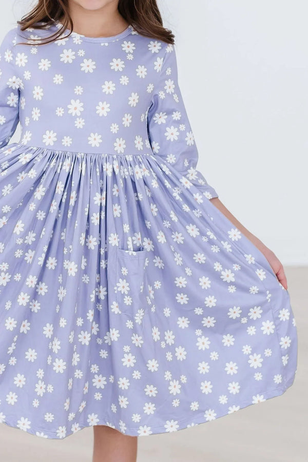 girl wearing lavender twirl dress for girls with white daisy print holding skirt out