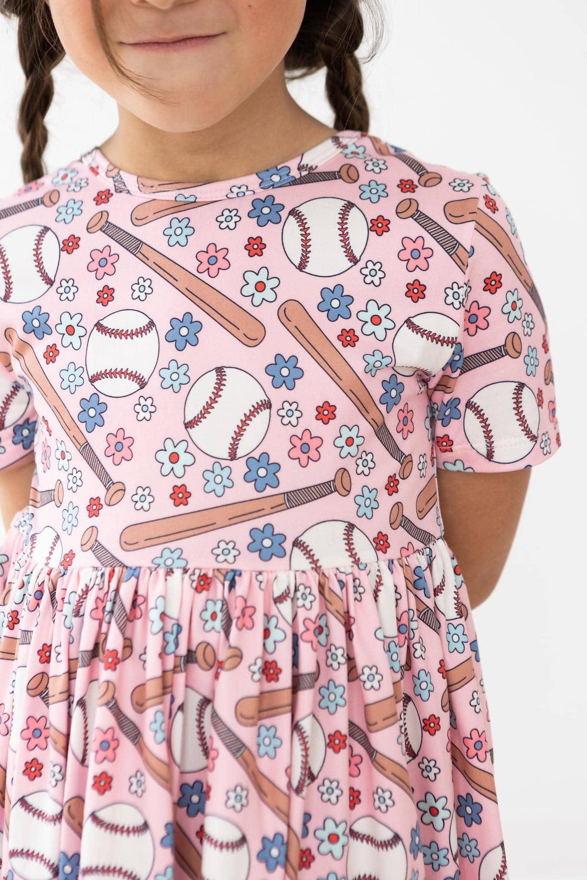 young girl wearing pink baseball print twirl dress for girls with pockets and short sleeves