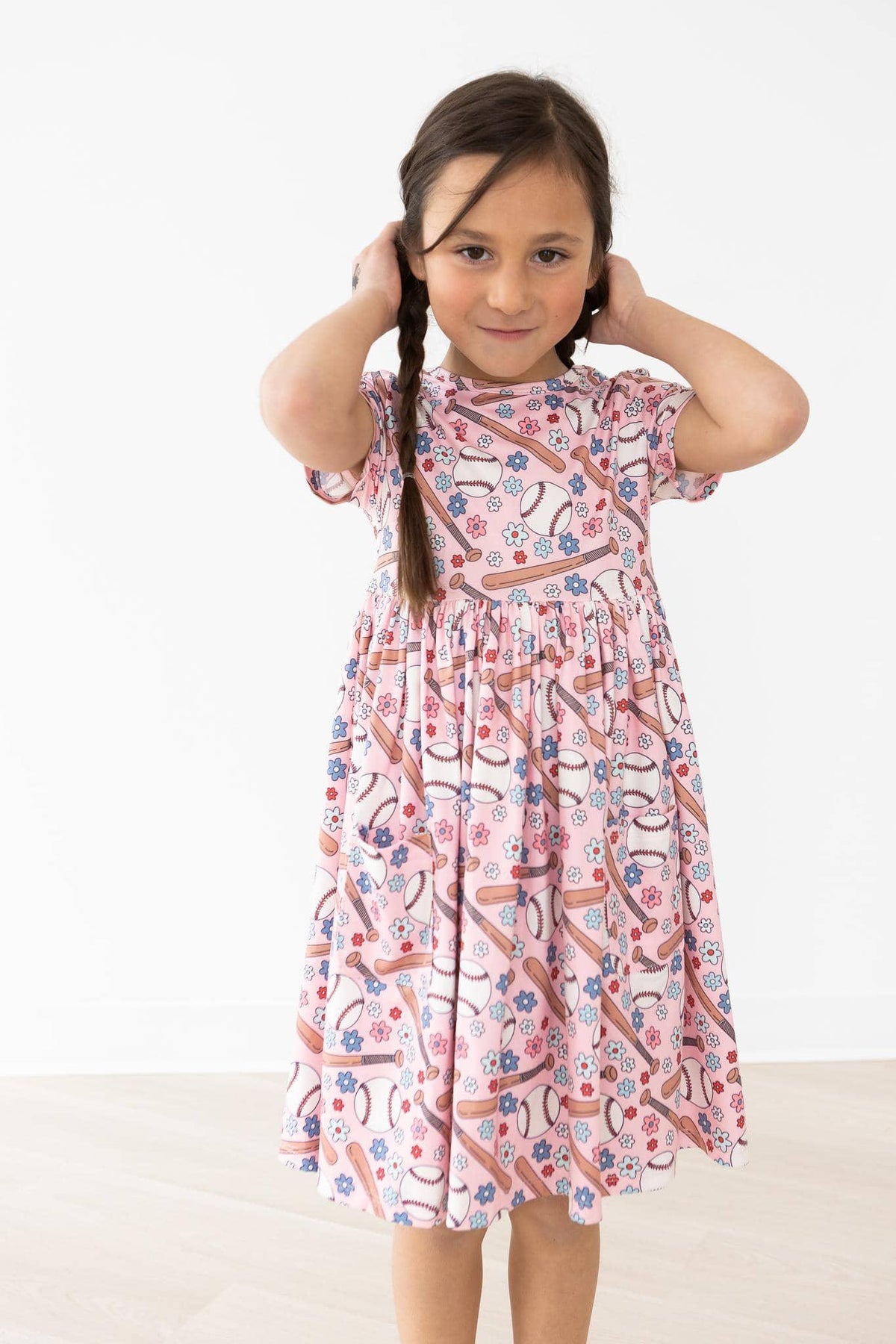 young girl wearing pink patterned twirl dress for girls standing and adjusting her hair