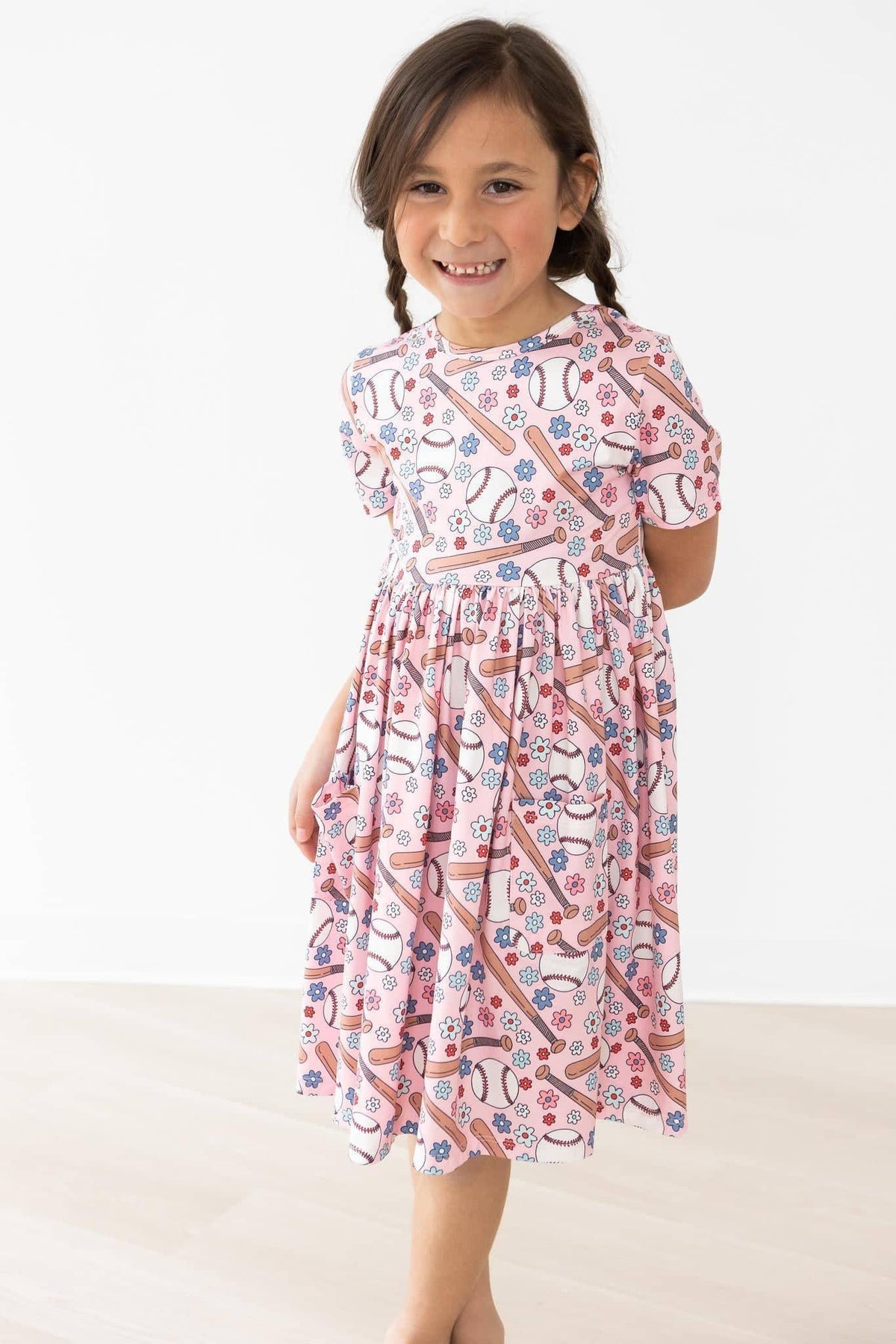 young girl wearing pink patterned twirl dress for girls standing and smiling