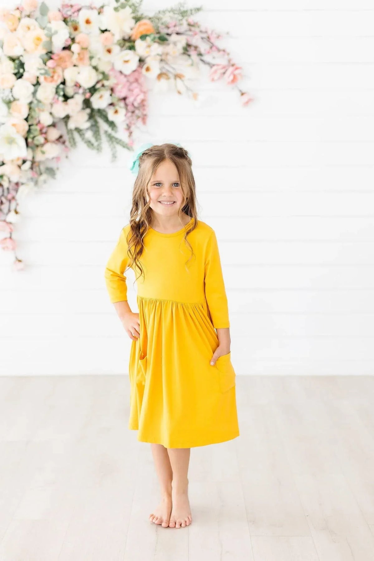 young girl wearing yellow Mila & Rose twirl dress for girls standing barefoot with hands in pockets