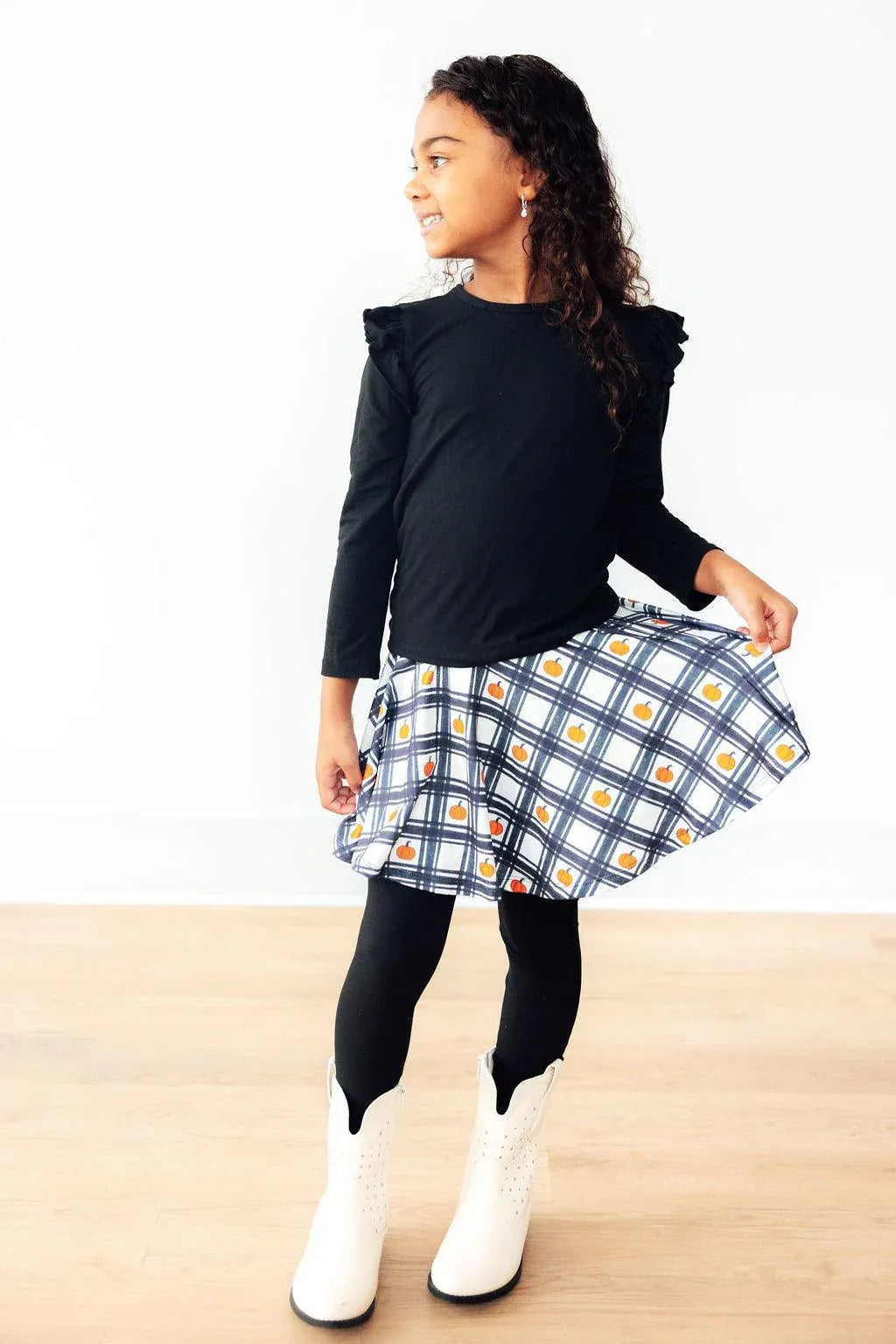 Girls black long sleeve top with ruffle shoulders and white plaid twirl skegging in toddler size