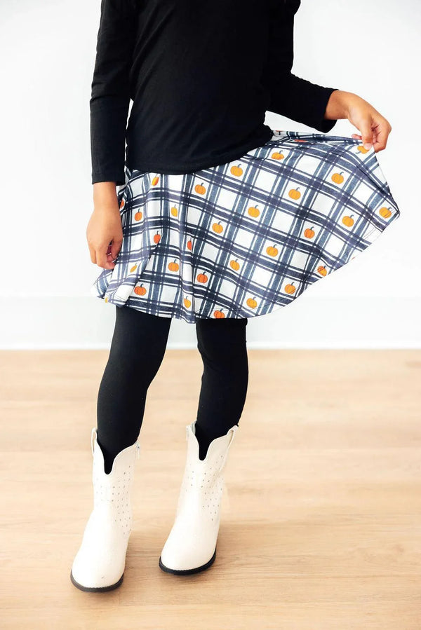 Girls black twirl skegging with white and blue plaid skirt featuring small orange pumpkin pattern