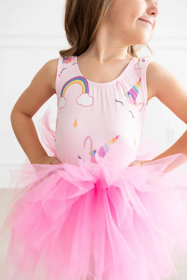 young girl wearing pink unicorn tutu leotard for girls with rainbow and unicorn prints posing with hands on hips