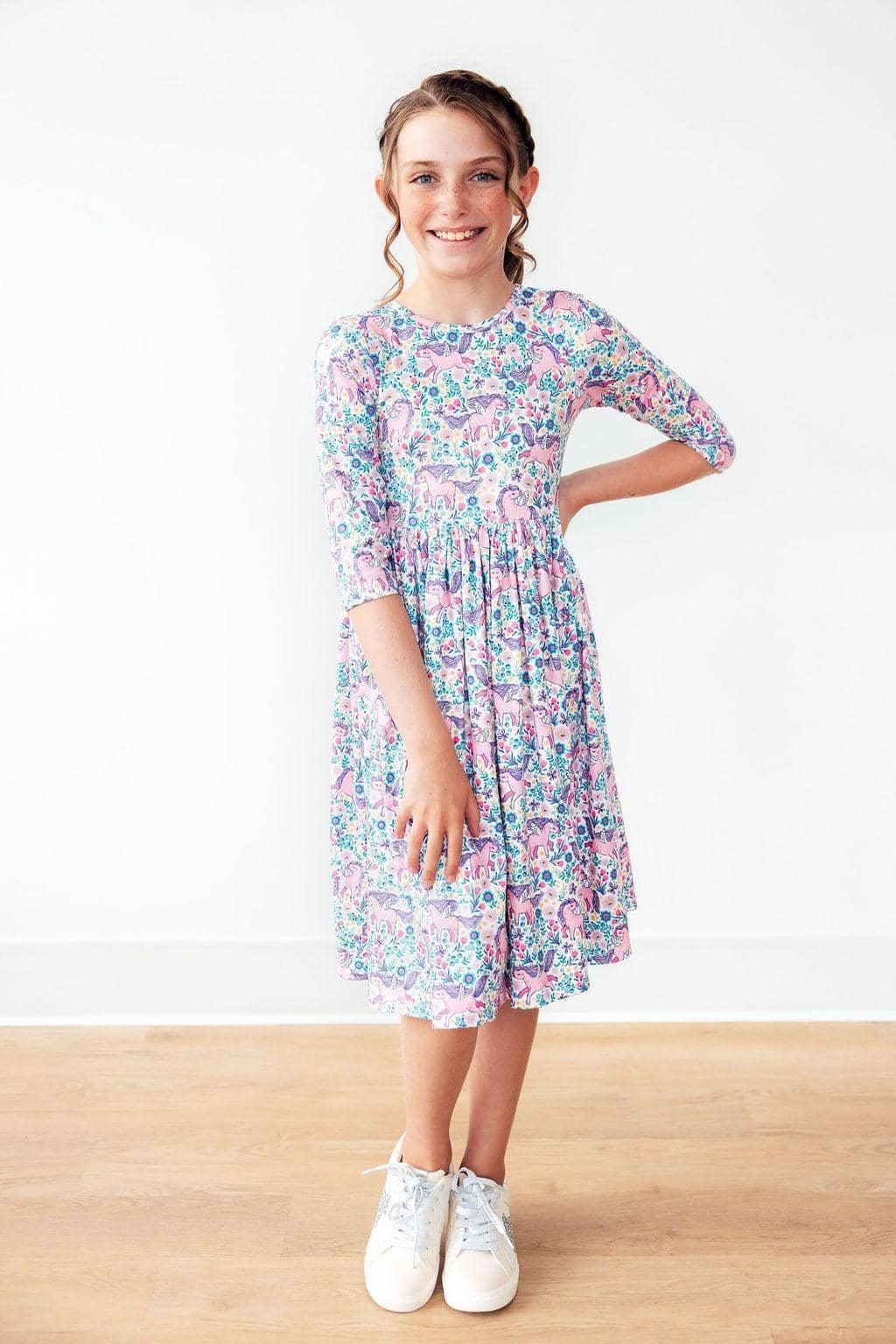Girl wearing pink and blue unicorn twirl dress for girls with 3 quarter sleeves standing and smiling