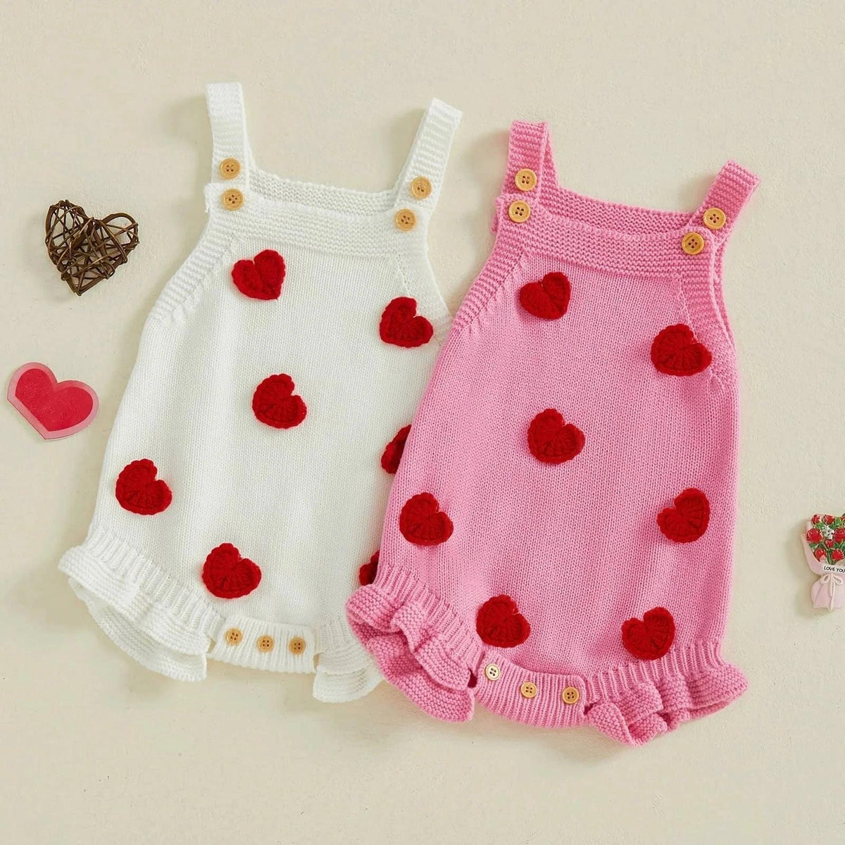 Pink and white knitted Valentine's Day baby romper with red heart accents and wooden buttons