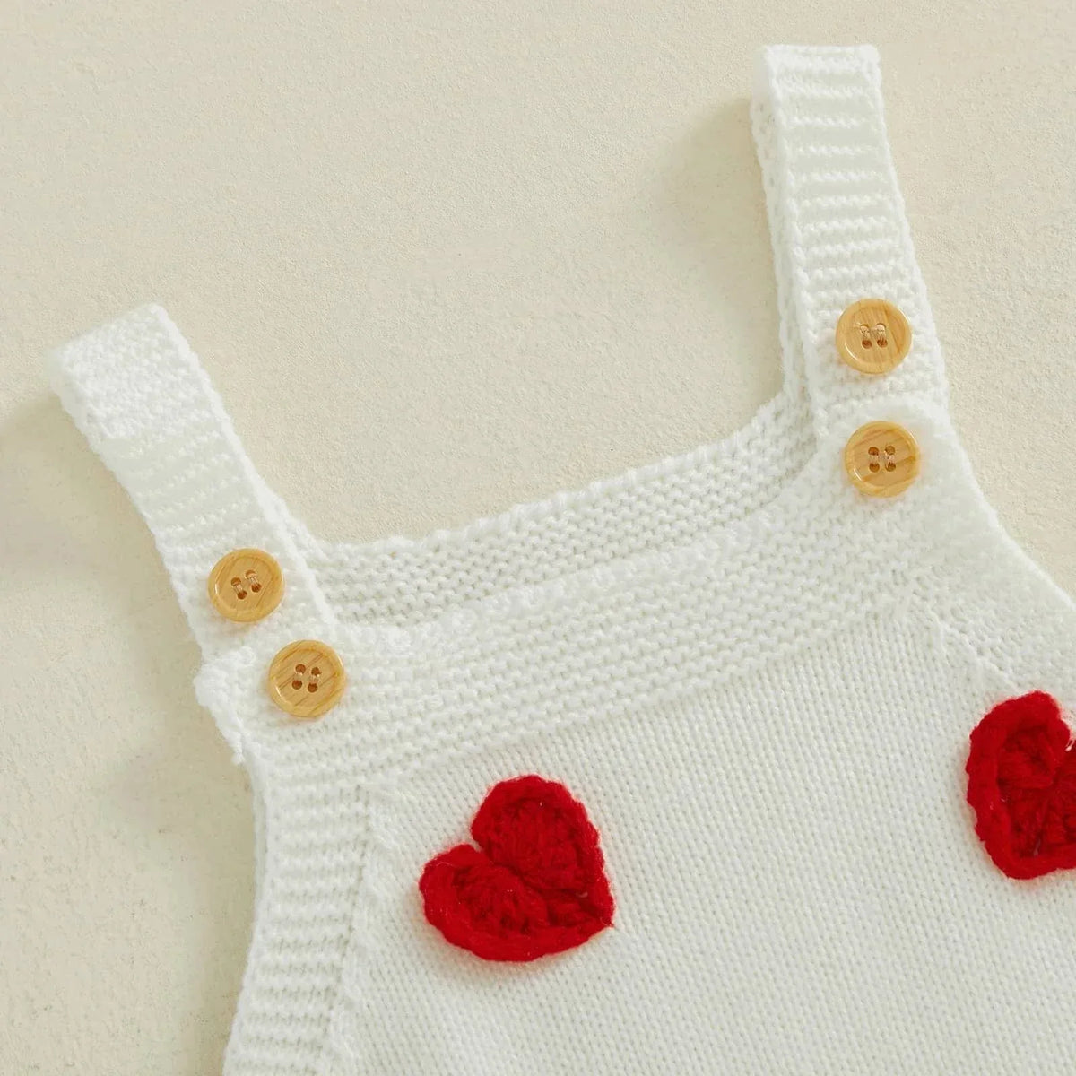 White knitted cotton Valentine's Day baby romper with red heart details and wooden buttons