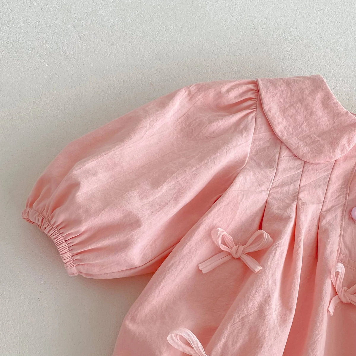 Soft pink baby girl bubble romper with puff sleeves and decorative bows for babies and kids