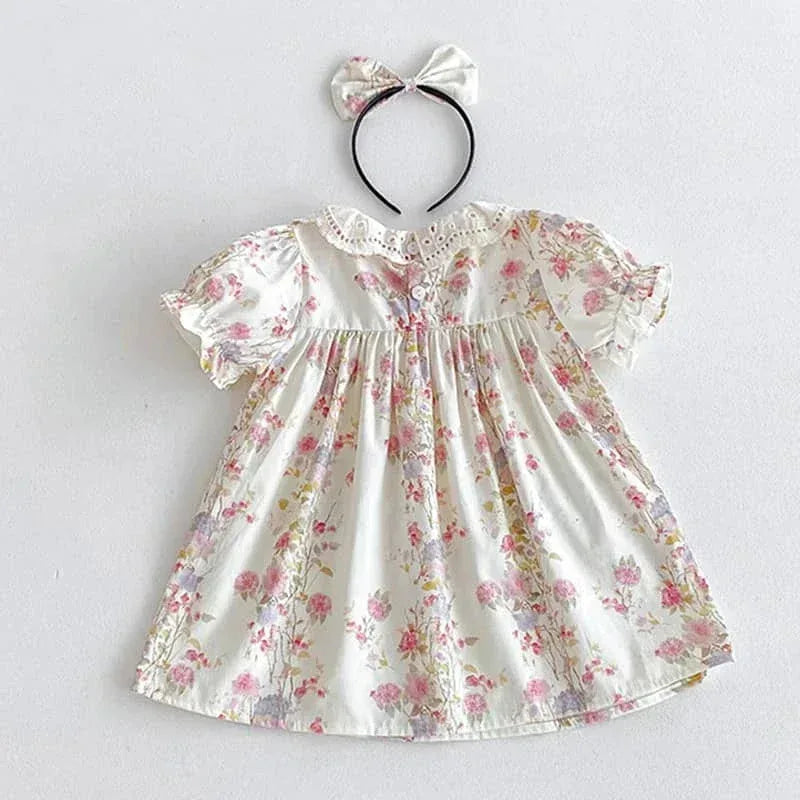 White cotton vintage baby girl outfit with pink floral print and matching fabric bow headband