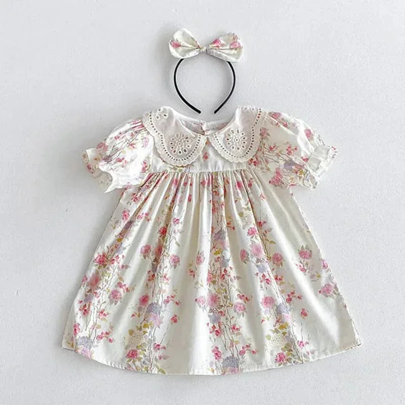 White cotton vintage baby girl outfit with pink floral print and eyelet lace collar with matching headband