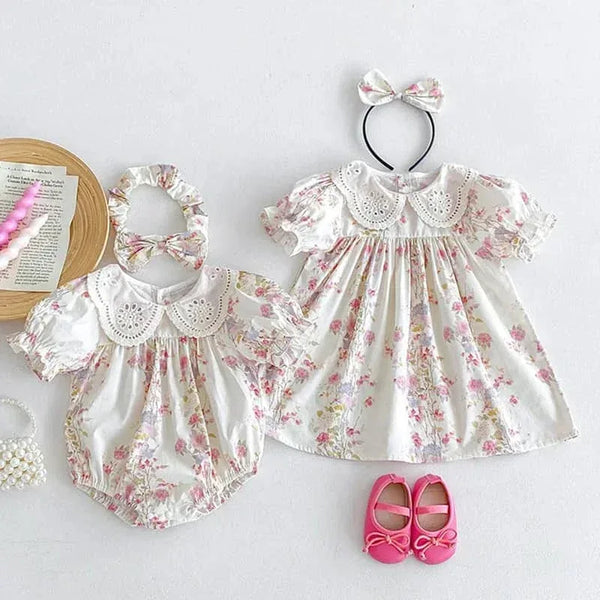 White cotton vintage baby girl outfit with pink floral print and eyelet lace collar including dress and romper