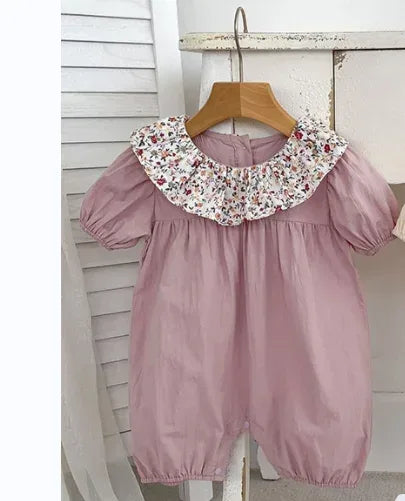 pink vintage floral baby romper with puff sleeves and floral collar hanging on wooden hanger