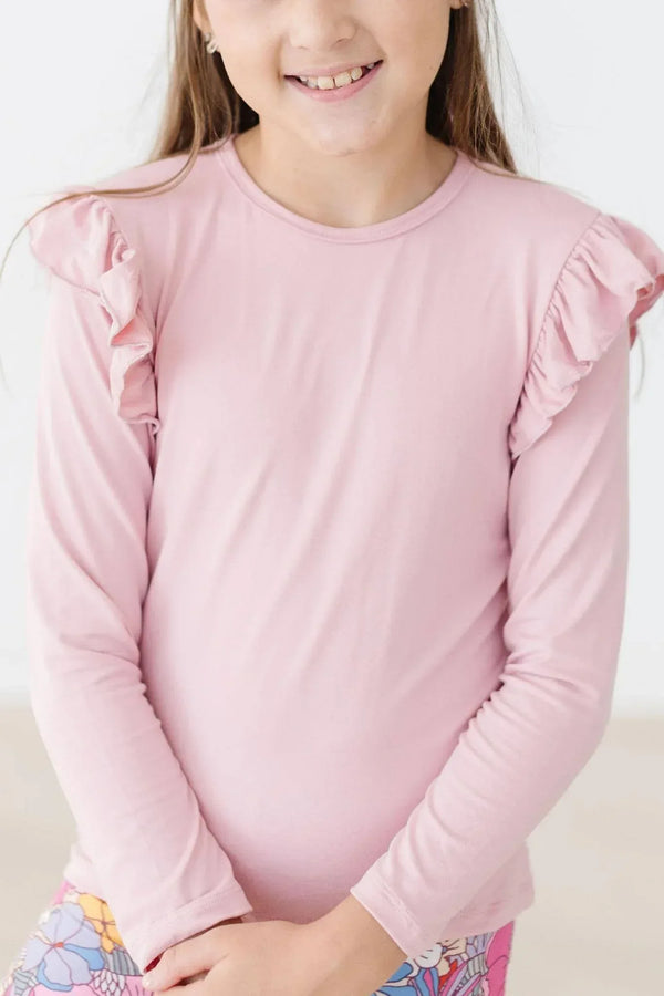 young girl wearing vintage pink ruffle long sleeve tee standing with hands clasped