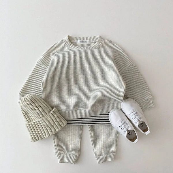 cream waffle cotton baby knit set for infants with long sleeve top, pants, matching hat, and white baby shoes