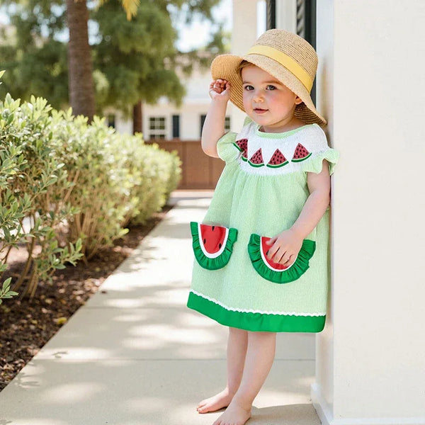 toddler girl wearing green watermelon baby dress with ruffle sleeves and watermelon pocket details