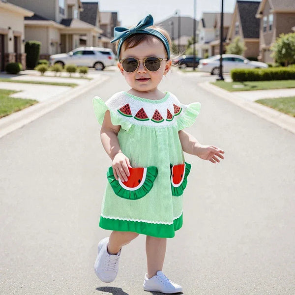 Toddler girl wearing green watermelon baby dress with ruffle sleeves and watermelon pocket details