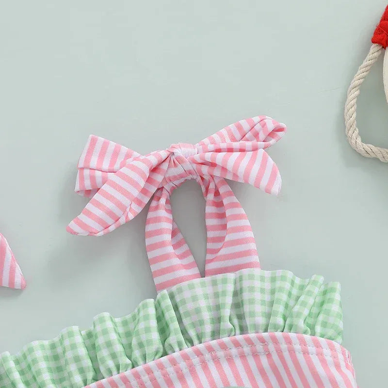 Close-up of pink and white striped tie strap with green gingham ruffle made of soft cotton in watermelon baby swimsuit