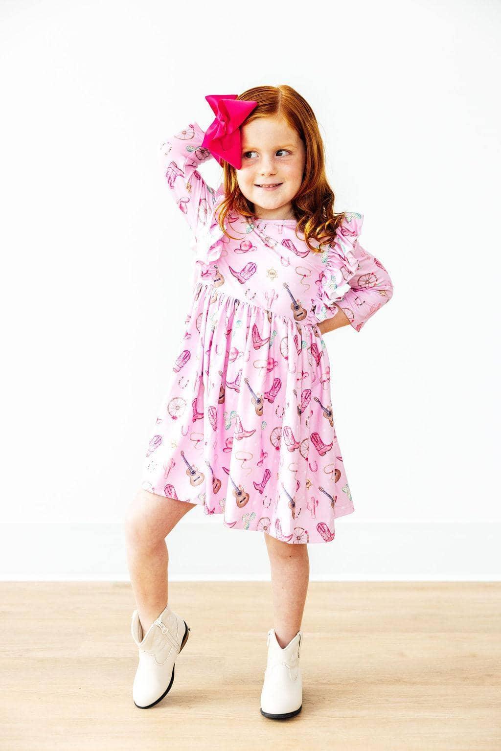 Young girl wearing pink Mila & Rose kids twirl ruffle dress with western dress for girls pattern posing with hand on hip