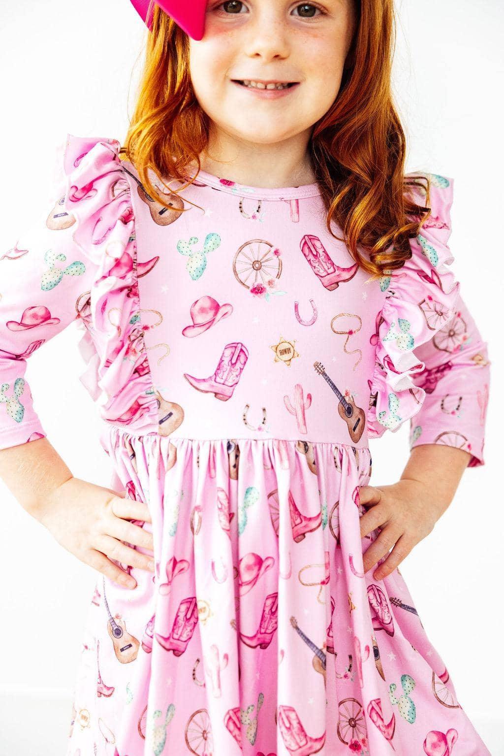 young girl wearing pink western dress for girls with ruffled sleeves smiling and posing