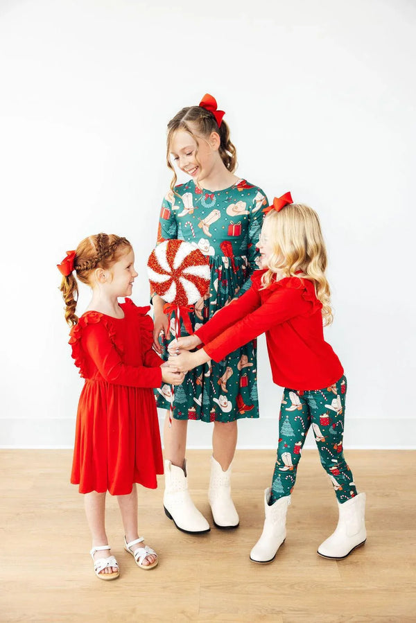 Mila & Rose girls western girls leggings in green holiday print worn by young girl with red sweater and white boots