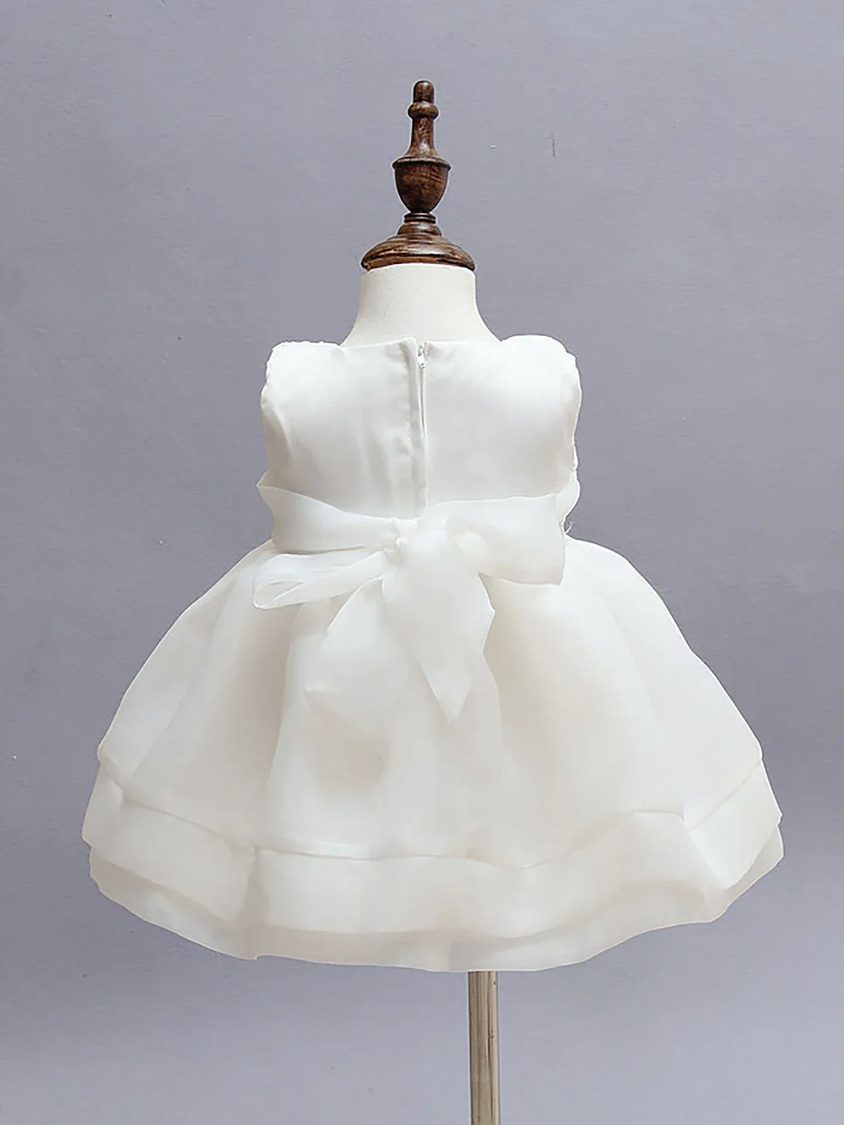 white chiffon baby dress set displayed on a toddler mannequin with a bow at the back