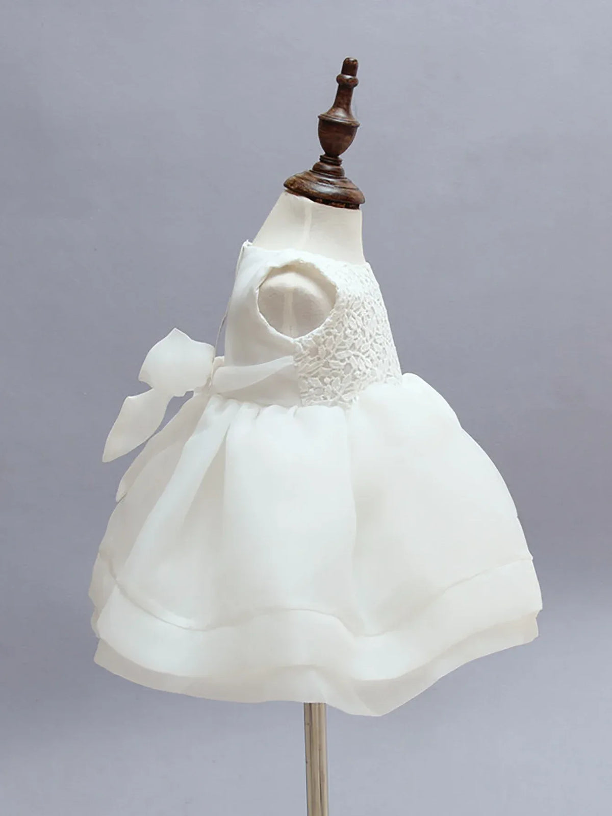 White chiffon baby dress set displayed on a mannequin showing delicate lace bodice and bow detail