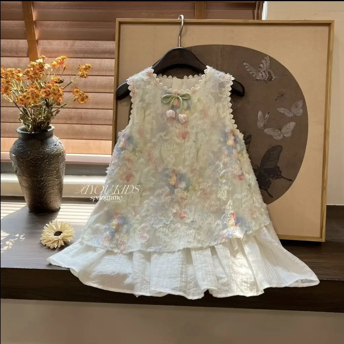 White elegant summer dress for toddlers with floral lace overlay and pompom bow detail