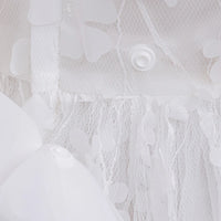 Close-up of white flower girl dress with headband showing floral lace and button details for baby