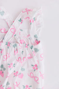 White ruffle cross back romper for little girls with pink strawberries and bows pattern, toddler size