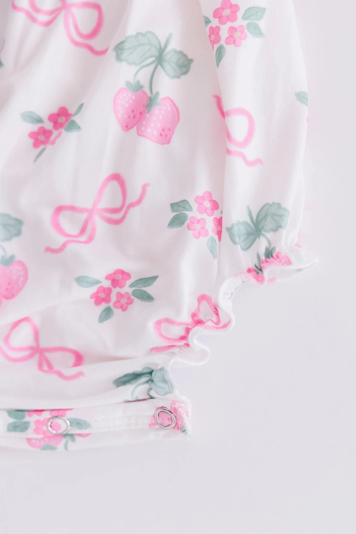Mila & Rose ruffle cross back romper for little girls with pink strawberry and bow print in white fabric
