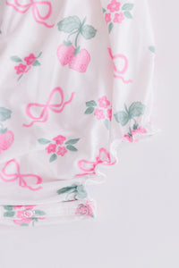 Mila & Rose ruffle cross back romper for little girls with pink strawberry and bow print in white fabric