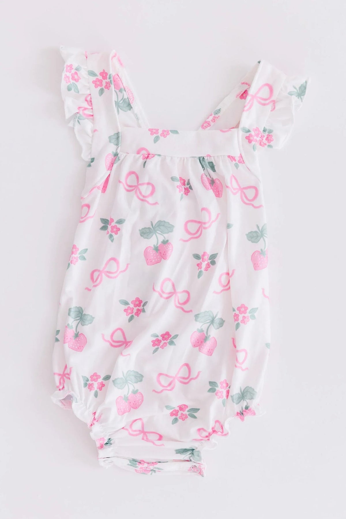 Mila & Rose ruffle cross back romper for little girls in white with pink bows and strawberry print