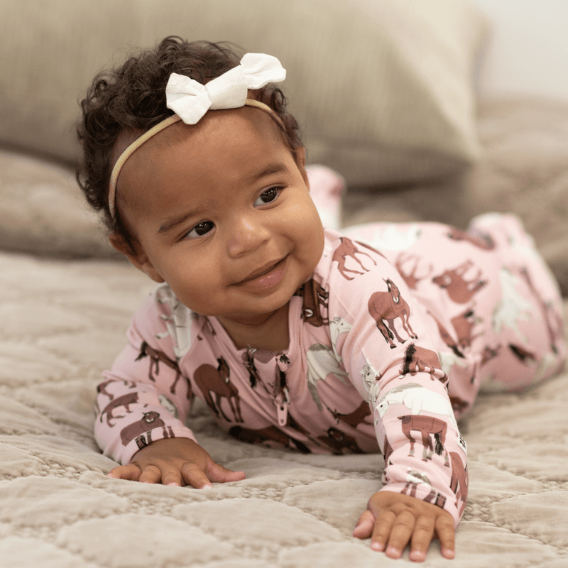 Baby wearing pink Wild Horses Zipper Footie with horse print, fold-over cuffs, and two-way zipper.